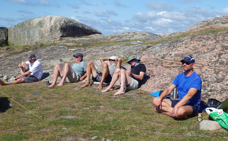 Bild. Paddelgänget sitter lutade mot en klippa.