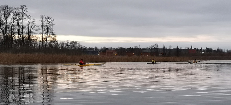 Bild. Tre kajaker på ån i skymningen.