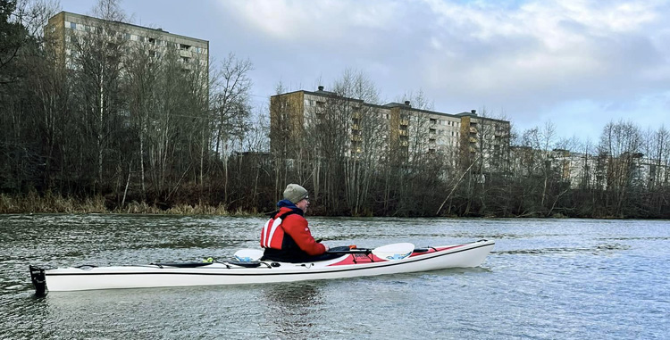 Bild. Johan paddlar 6- och 10-våningshus i bakgrunden.